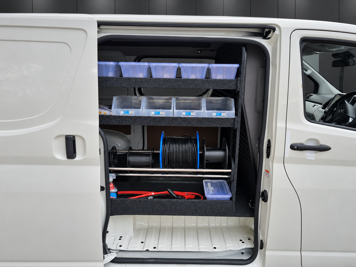 Full-height van shelving behind the driver's seat with storage bins and cable-roll holders