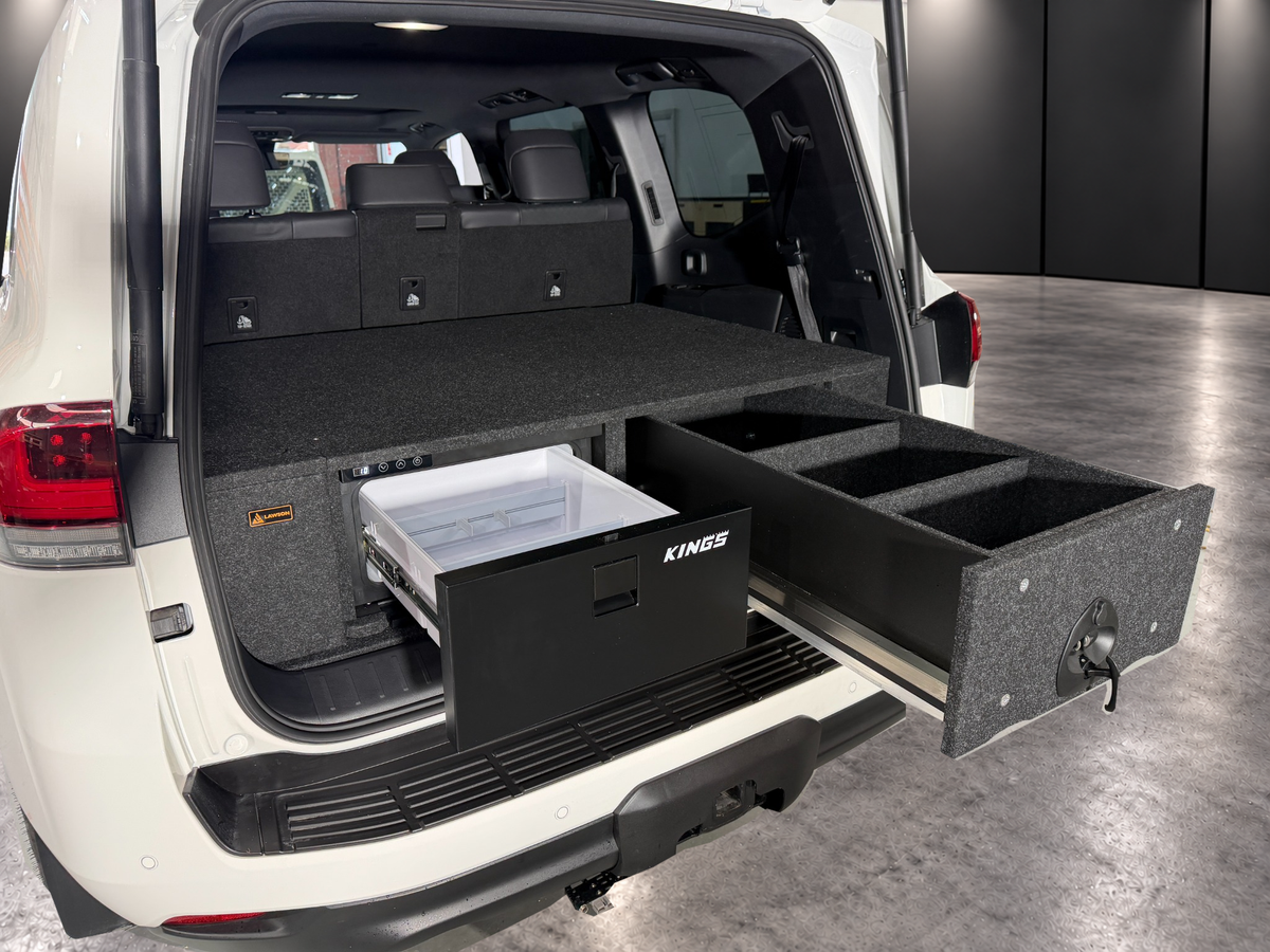 LandCruiser 300 Kings 30 litre fridge and matching raised drawer open, showing two carpeted dividers; wagon installation example, ute layout differs